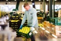 strong man working on fruit sorting line, carrying box with apples in storage