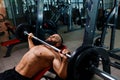 A strong man working out exercises with a barbell on a gym background. An athletic guy keeps barbell plate in hands. Royalty Free Stock Photo