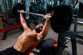 A strong man working out exercises with a barbell on a gym background. An athletic guy keeps barbell plate in hands. Royalty Free Stock Photo