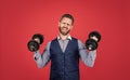 Strong manager in formal style lifting heavy dumbbells red background, strength Royalty Free Stock Photo