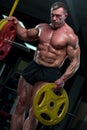 Strong mature man with relief body posing in gym