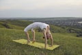 Fit mature woman practicing Urdhva Dhanurasana on quiet green hill in countryside Royalty Free Stock Photo