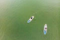 Strong men floating on a SUP boards in a beautiful bay on a sunny day. Aerial view of the men crosses the bay using the Royalty Free Stock Photo