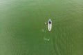 Strong men floating on a SUP boards in a beautiful bay on a sunny day. Aerial view of the men crosses the bay using the Royalty Free Stock Photo