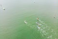 Strong men floating on a SUP boards in a beautiful bay on a sunny day. Aerial view of the men crosses the bay using the