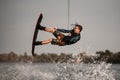 strong muscular guy jumps high and does somersault on wakeboard over the water Royalty Free Stock Photo