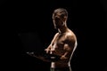 Strong muscular man holding laptop isolated on black background Royalty Free Stock Photo