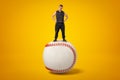 Strong muscular young man standing on big white baseball ball on yellow background Royalty Free Stock Photo