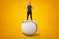 Strong muscular young man standing on big white baseball ball on yellow background Royalty Free Stock Photo