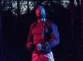 Strong muscular young man with weightlifting chains around his body and a fitness mask, working out in the park as evening Royalty Free Stock Photo