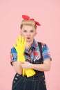 Strong pin-up styled blonde girl take on hand rubber yellow glove for cleaning. Woman in denim take on hand glove Royalty Free Stock Photo