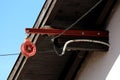 Strong plastic pulley mounted on metal pole on edge of family house roof next to electrical wires with clear blue sky in