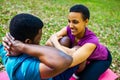 Strong and powerful afro american couple in love are working out abs exercises outside in park or forest