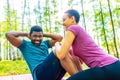 Strong and powerful afro american couple in love are working out abs exercises outside in park or forest
