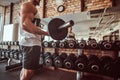 Strong powerful bodybuilder is doing his workout with barbell in gym