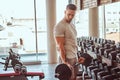 Strong powerful bodybuilder is doing his workout with barbell in gym