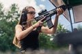 Strong powerful confident long-haired caucasian woman in a black tank top holding big black rifle with loupe preparing Royalty Free Stock Photo