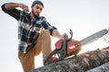 Professional lumberjack wearing plaid shirt fire up chainsaw on sawmill