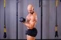 Strong ripped bald man working out with dumbbells in gym. Sport,