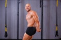 Strong ripped bold man demonstrating big muscles in gym. Sport,