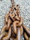 Strong rusty chain lies on small stones Royalty Free Stock Photo