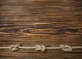 Strong sea knot on the rope. Old brown wooden background. Texture to design Royalty Free Stock Photo