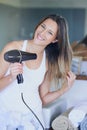 Strong and shiny from root to tip. Portrait of a beautiful young woman drying her hair with a hairdryer in the bathroom Royalty Free Stock Photo