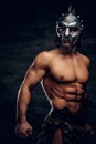 Strong shirtless gladiator in helmet is showing his muscules