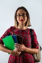 Strong smart girl holding books in one hand in glasses on beautiful background.