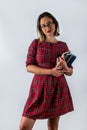 Strong smart girl holding books in one hand in glasses isolated on beautiful background.