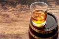 Strong spirit, masculine or macho lifestyle and whisky distillery concept with glass of good bourbon on the rocks and oak barrel Royalty Free Stock Photo