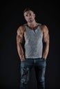 Strong sportsman show fit muscular arms biceps triceps muscles wearing casual undershirt with jeans black background