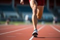 Strong sportsman in sneakers and shorts runs along track at sports stadium closeup