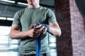 Strong sportsman wearing khaki shirt holding blue wrist wraps