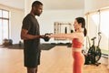 Strong sportswoman doing exercise with dumbbells at gym while coach assisting Royalty Free Stock Photo