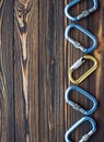 Strong steel. Isolated photo of climbing equipment. Parts of carabiners lying on the wooden table