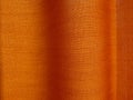 Strong sunshine filtering through woven textile textured orange color curtain drapery