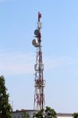 Strong tall cell phone red and white antenna tower with multiple antennas and transmitters on top of office building