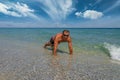 Strong tanned man in sunglasses doing plank exercise at seaside. Smiling sportsman train workout at sea during vacation