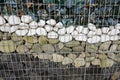 Strong wall with different stones made from pebbles inside of galvanized wire