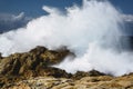 Crash of a wave against the rocks of the cliff causing a high collision and spraying water everywhere