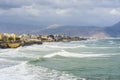Strong waves against the background of the city and mountains in Greece