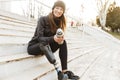 Strong willed handicapped woman in black tracksuit with prosthetic leg laughing, while sitting at the street stairs with thermos