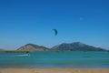 Strong winds pull female kiteboarder along the calm surface of the blue sea.