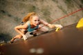 Strong woman and business success concept. Young caucasian pretty woman practicing climbing on artificial rock wall