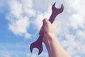 Hand holding up big wrench in the sky Royalty Free Stock Photo