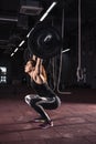 Strong woman lifting barbell as a part of crossfit exercise rout