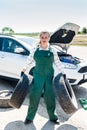 Strong woman, mechanic, posing with tyres in hands Royalty Free Stock Photo