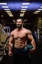 Happy smiling strong young bearded athlete with medicine heavy ball in blue lit night sport gym Royalty Free Stock Photo