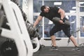 Strong young bearded caucasian man in black sportswear pulling heavy weight dumbbell with one hand training back and Royalty Free Stock Photo